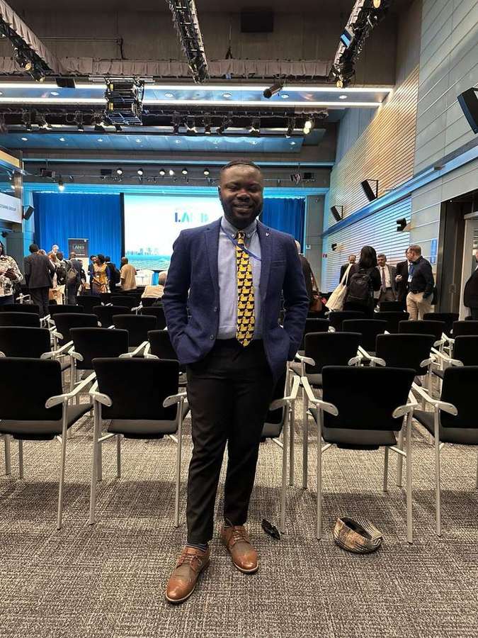 Elvis Kwame Ofori standing in a conference room at the World Bank LAND Conference in Washington DC